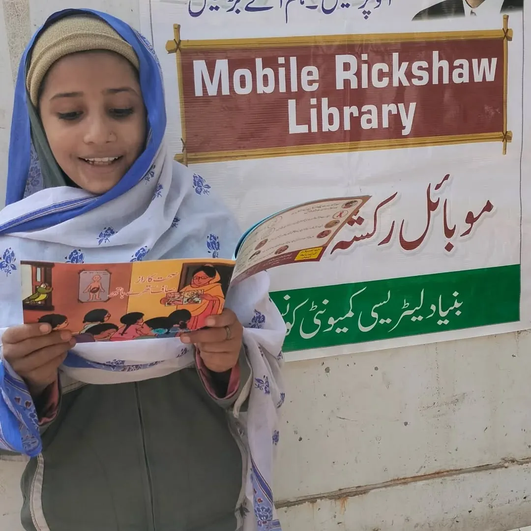 A girl reads a book from the Mobile Rickshaw Library